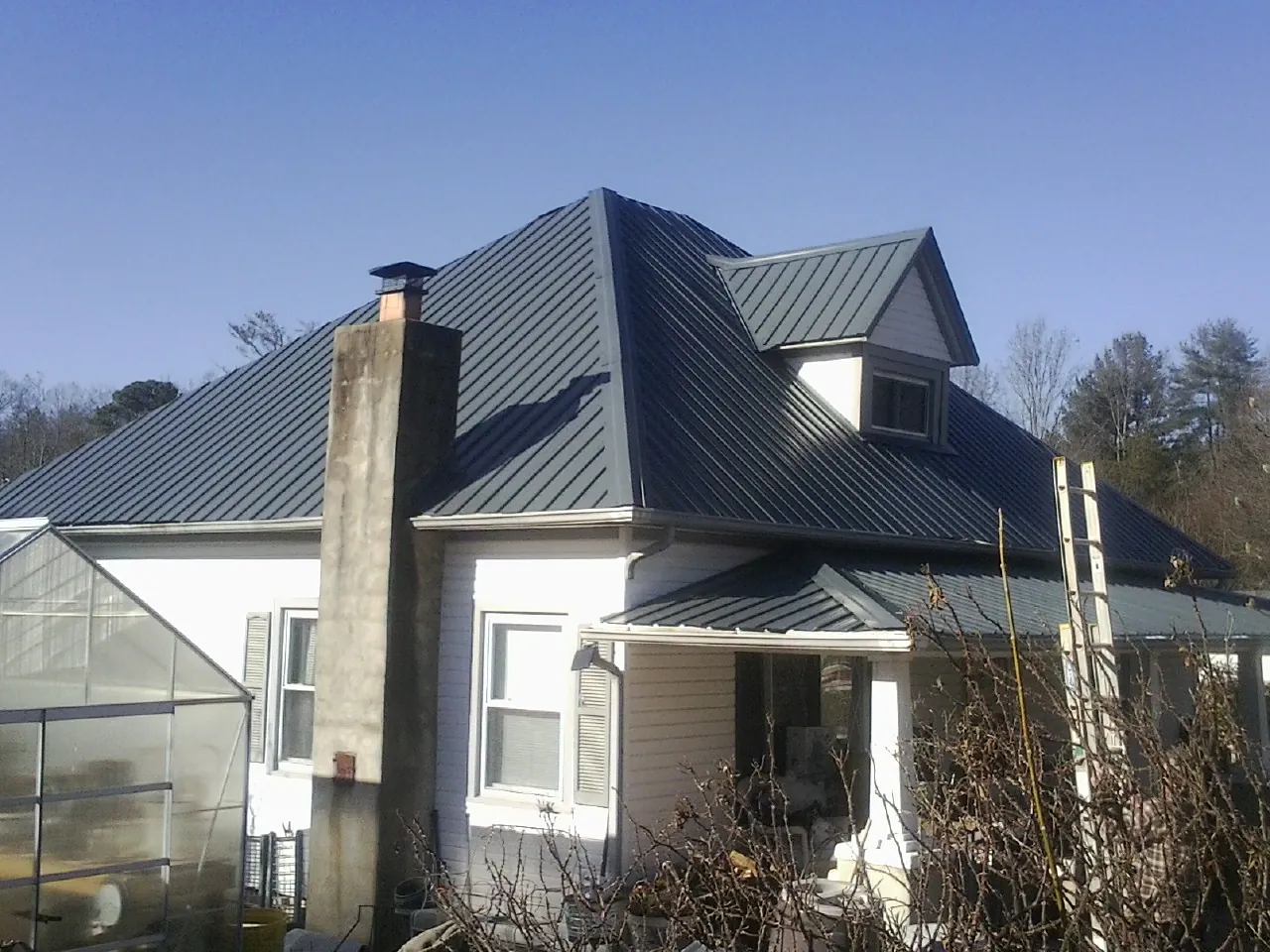 Dark blue standing seam metal roof on a white farmhouse with dormer — Slate & Tile Roof Repair by Roofing Brothers in Talent