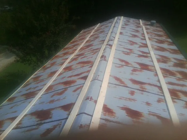 Rusted metal roof panels with new wood purlins before replacement — Storm Damage Roof Repair in Talent by Roofing Brothers
