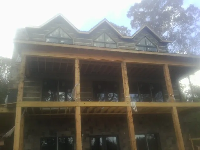 Dormers and porch framing on a large log home under construction — Roof Coating work by our crew in Talent