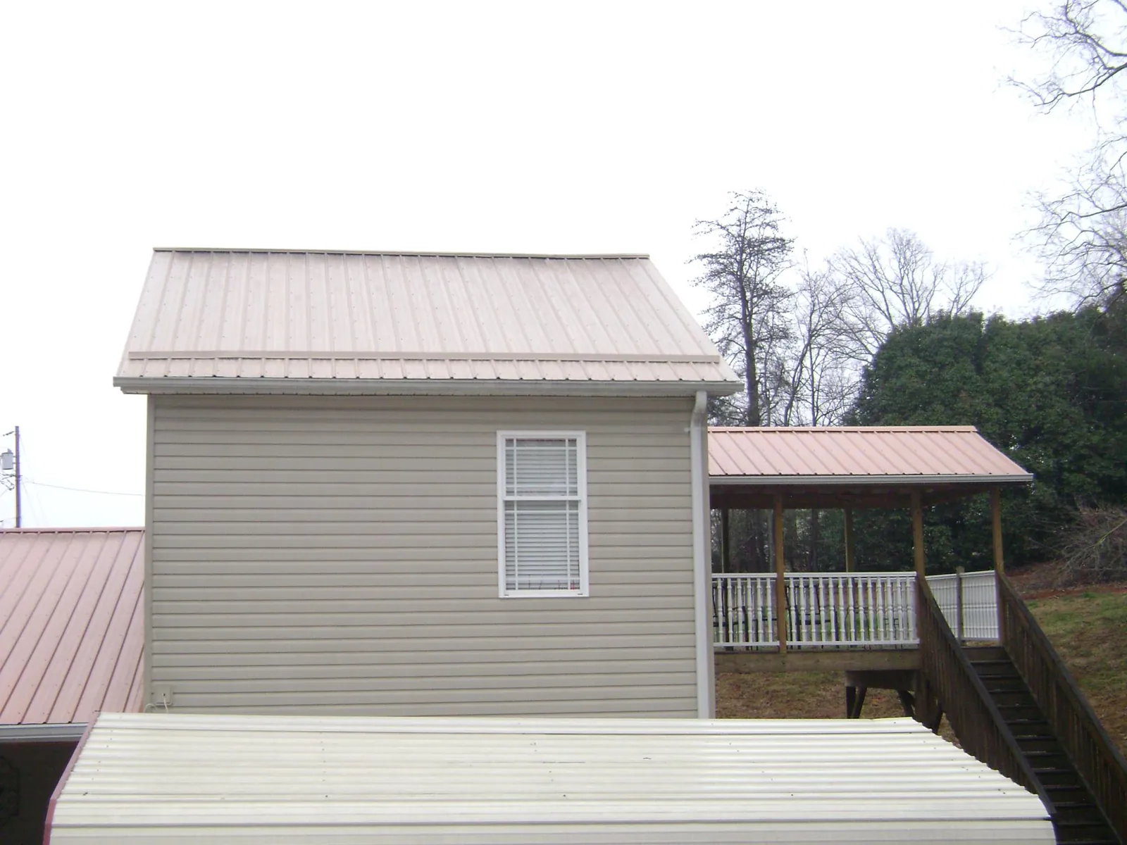 Tan metal roofs on a two story addition and attached porch, from a Roof Replacement job in Talent