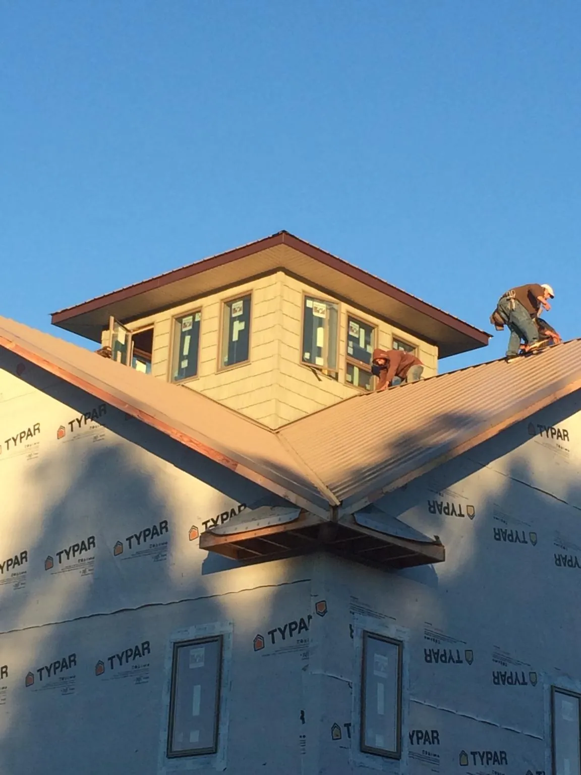 Roofers working around a rooftop cupola on a new metal roof at sunset — Roof Waterproofing in Talent by Roofing Brothers